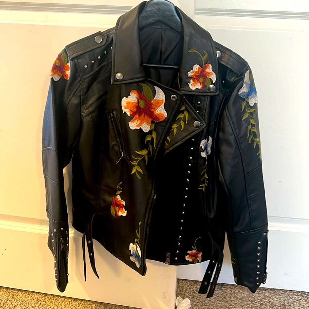 Leather jacket with floral, studded with zip sleeves and zips up.